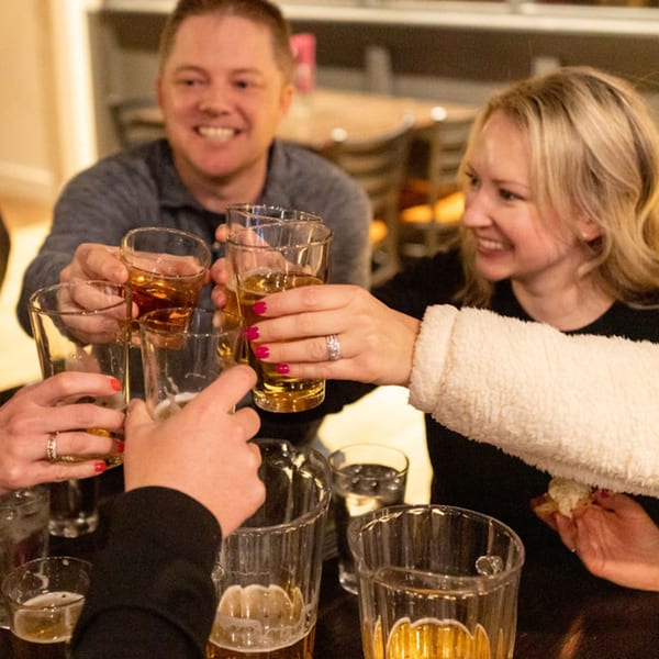 Friends toasting with beer glasses at a restaurant, smiling and enjoying their time.